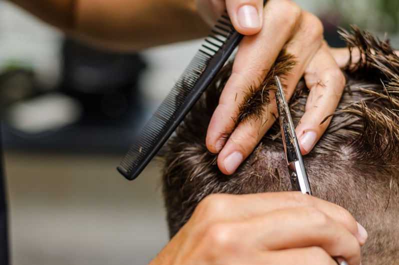 Person getting a haircut, close-up of scissors and comb in action.