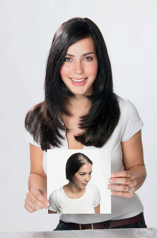Woman holding a photo showing hair transformation, smiling at camera.