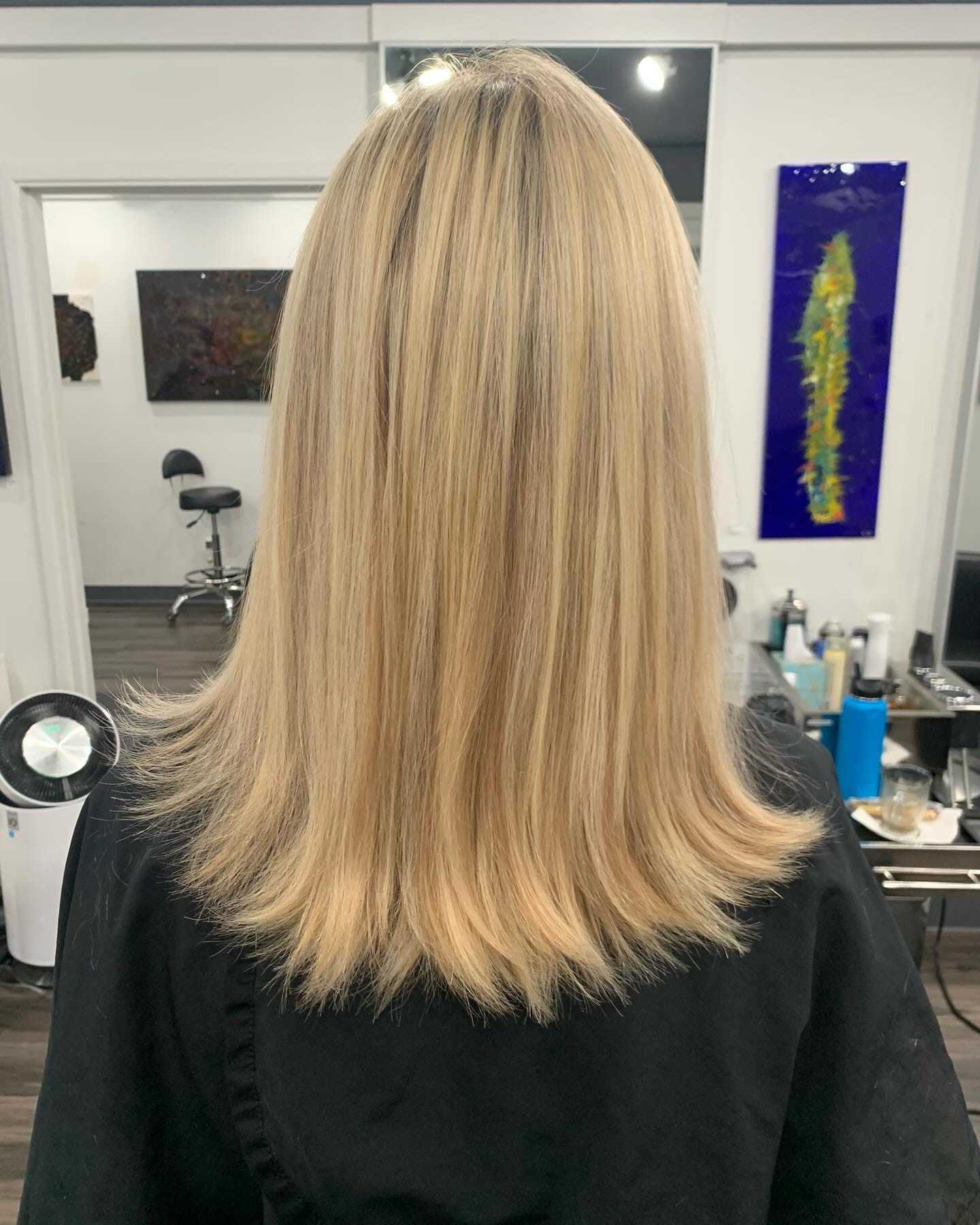 Blonde hair with straight haircut in a salon setting, seen from the back.
